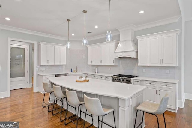 kitchen featuring custom exhaust hood, a center island, white cabinets, and a kitchen breakfast bar