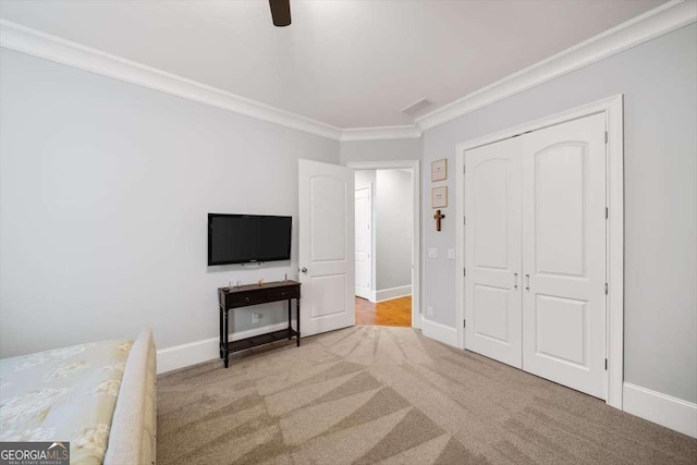 bedroom with crown molding, a closet, ceiling fan, and carpet