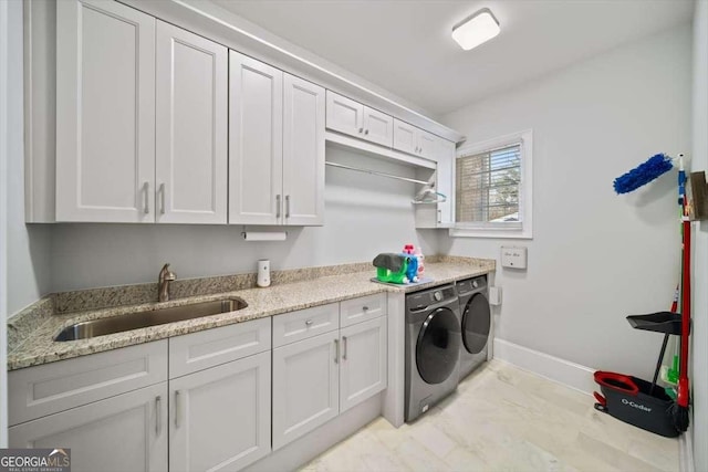 washroom with cabinets, washing machine and dryer, and sink