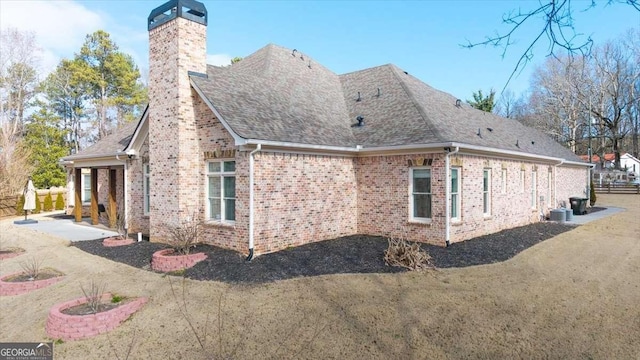 view of side of property with central AC unit, a yard, and a patio