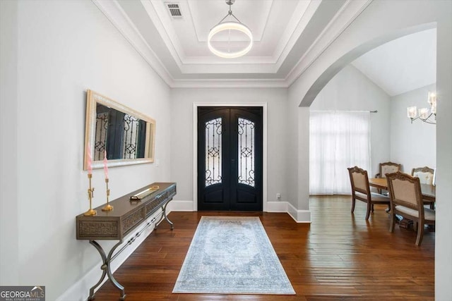 entrance foyer with a raised ceiling, a chandelier, dark hardwood / wood-style flooring, and french doors