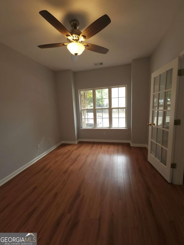 empty room featuring dark wood-type flooring and ceiling fan