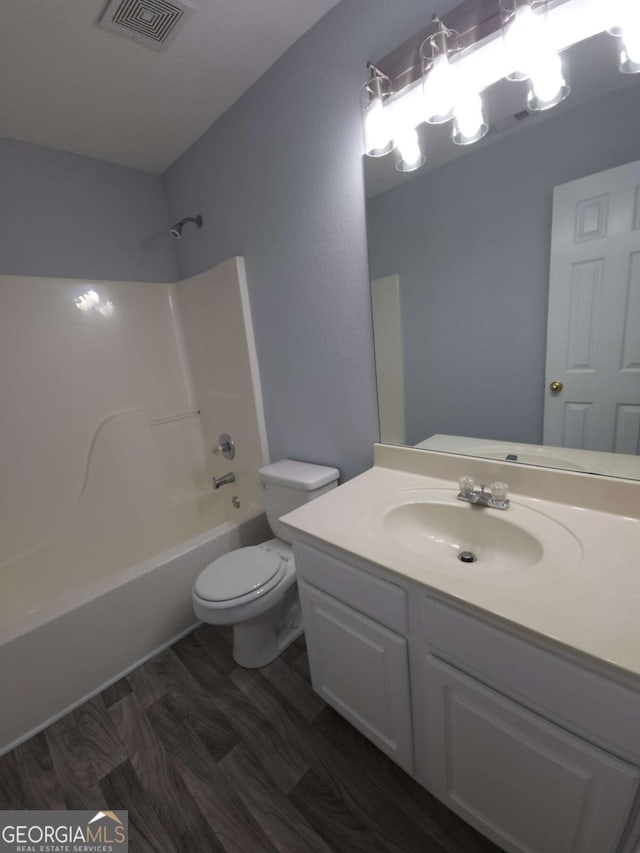 full bathroom featuring vanity, tub / shower combination, hardwood / wood-style floors, and toilet