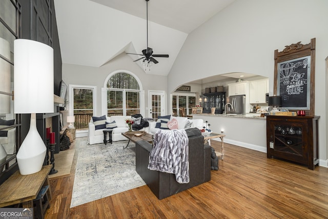 living room featuring hardwood / wood-style flooring, ceiling fan, and high vaulted ceiling