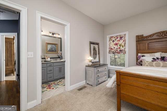 bedroom featuring connected bathroom and light colored carpet