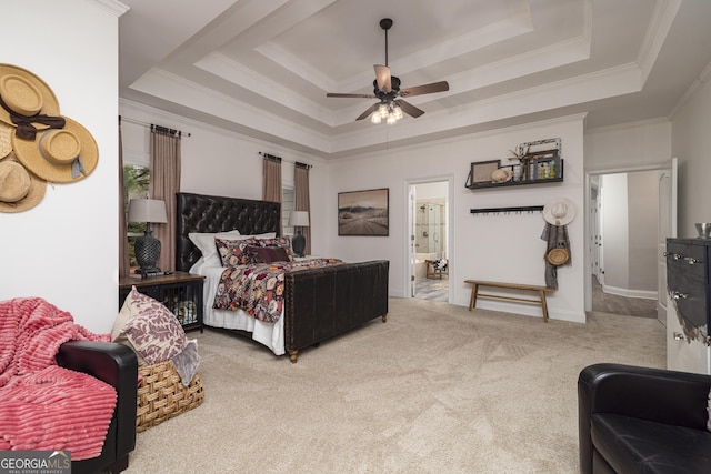 bedroom with ceiling fan, ensuite bathroom, a tray ceiling, carpet floors, and ornamental molding