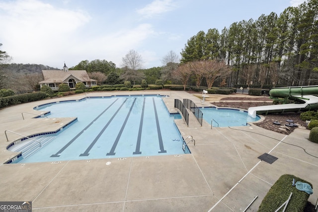 view of swimming pool with a water slide and a patio