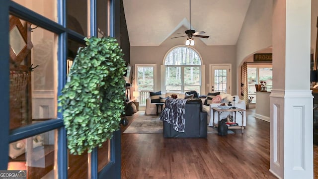 living room featuring ceiling fan, dark hardwood / wood-style floors, high vaulted ceiling, and ornate columns