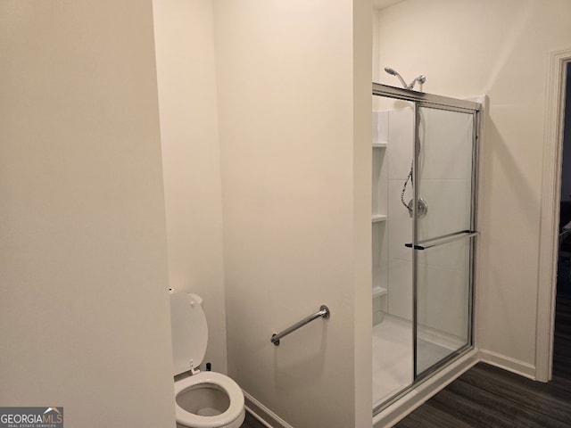 bathroom featuring hardwood / wood-style floors, a shower with shower door, and toilet