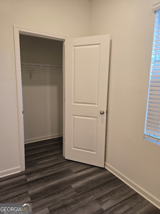 unfurnished bedroom featuring dark hardwood / wood-style flooring and a closet