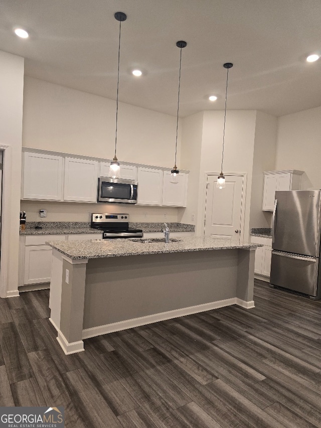 kitchen featuring white cabinetry, hanging light fixtures, a kitchen island with sink, stainless steel appliances, and light stone countertops