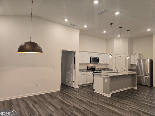 kitchen featuring appliances with stainless steel finishes, a towering ceiling, an island with sink, white cabinets, and decorative light fixtures