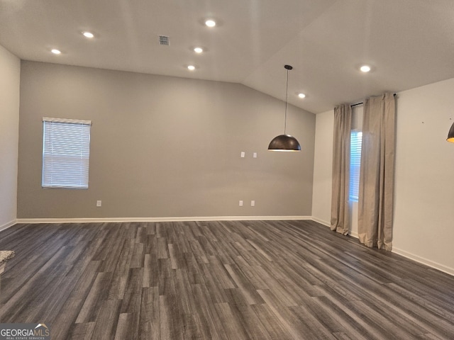 spare room with lofted ceiling, a wealth of natural light, and dark wood-type flooring