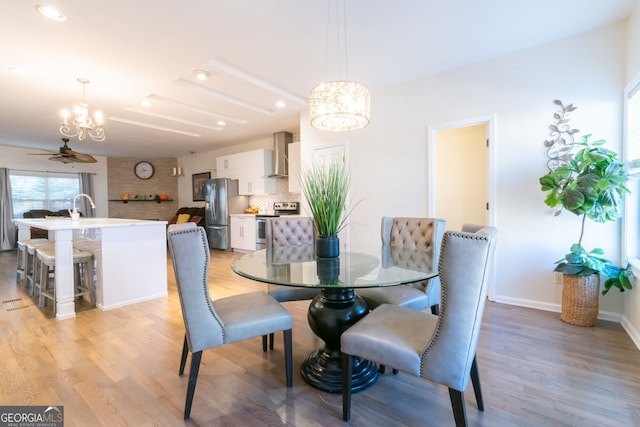 dining room with ceiling fan with notable chandelier and light wood-type flooring