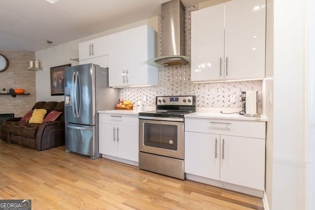 kitchen featuring white cabinetry, backsplash, stainless steel appliances, wall chimney range hood, and light wood-type flooring