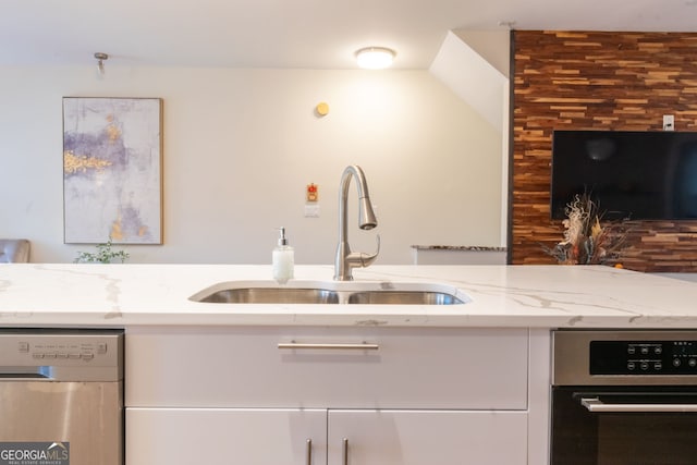 kitchen featuring stainless steel appliances, sink, white cabinets, and light stone counters