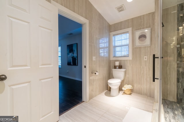 bathroom with tile walls, a shower with shower door, tile patterned floors, and toilet