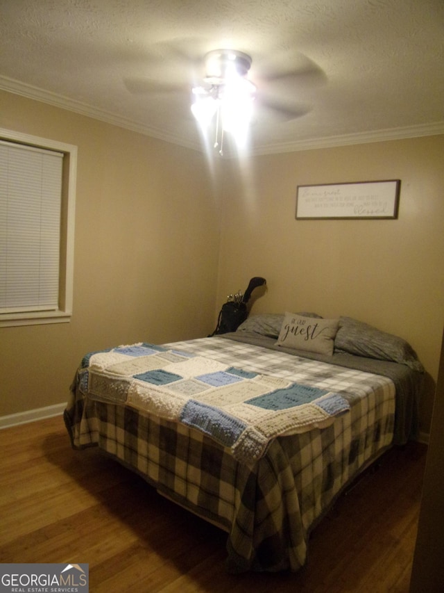 bedroom with hardwood / wood-style floors, crown molding, and ceiling fan