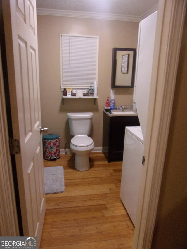 bathroom with vanity, crown molding, wood-type flooring, and toilet