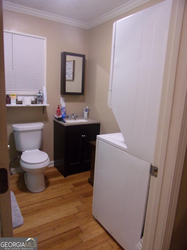 bathroom with ornamental molding, vanity, toilet, and wood-type flooring