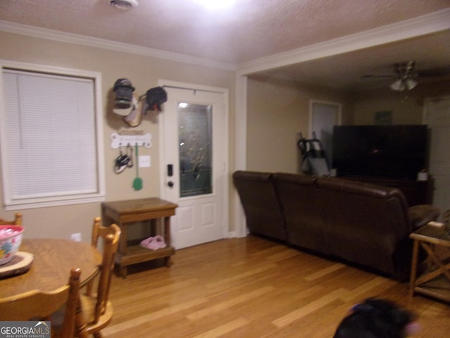 living room featuring ornamental molding, light hardwood / wood-style floors, and ceiling fan