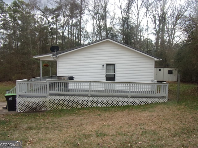 rear view of house featuring a wooden deck, a yard, and a storage unit