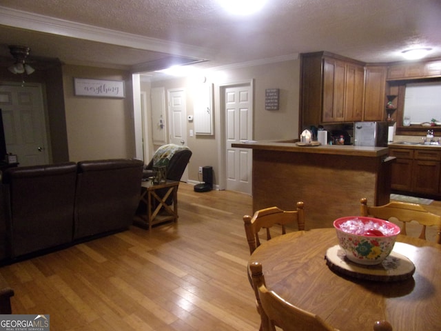 dining room featuring crown molding, a textured ceiling, and light wood-type flooring