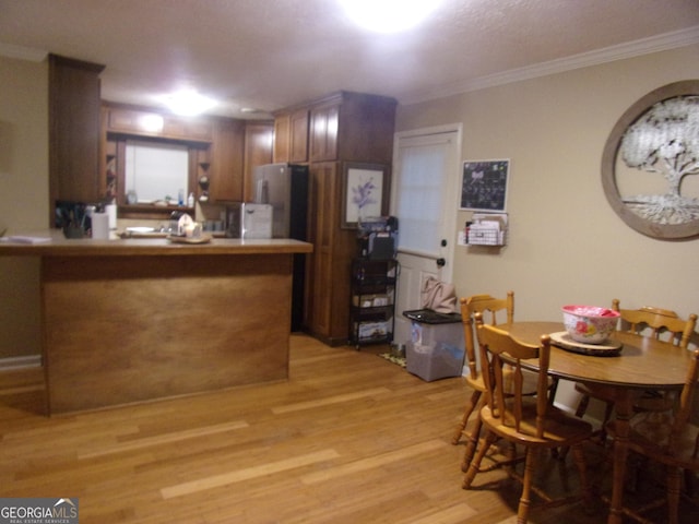 kitchen with ornamental molding, stainless steel fridge, kitchen peninsula, and light hardwood / wood-style flooring