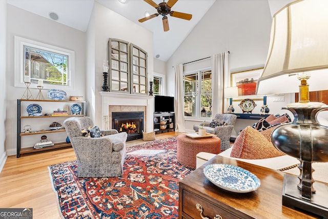 living room with ceiling fan, high vaulted ceiling, and light hardwood / wood-style floors