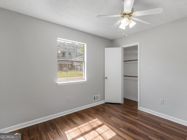 unfurnished bedroom featuring ceiling fan, dark wood-type flooring, a textured ceiling, and a closet