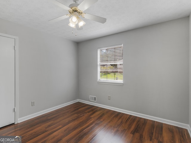 empty room featuring ceiling fan, dark hardwood / wood-style flooring, and a textured ceiling