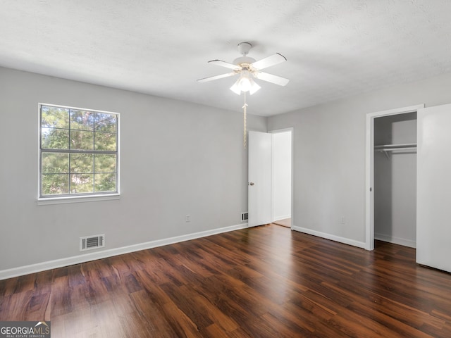 unfurnished bedroom featuring dark wood-type flooring, ceiling fan, and a textured ceiling