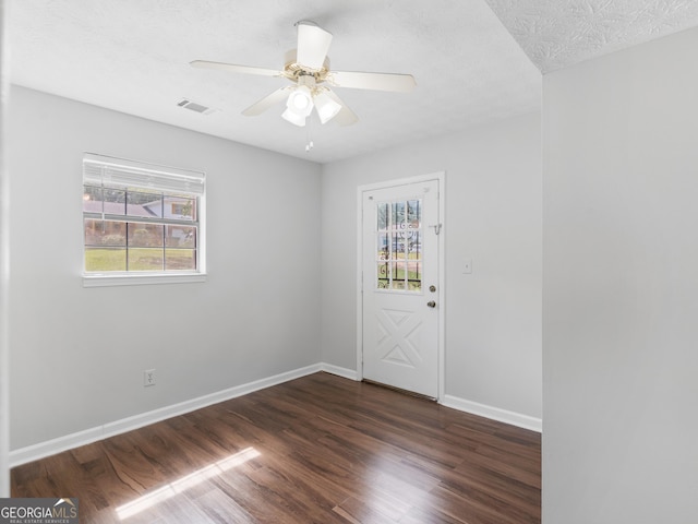 empty room with dark hardwood / wood-style floors, a textured ceiling, and ceiling fan