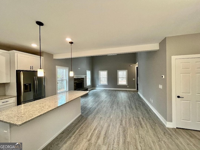 kitchen featuring white cabinetry, hardwood / wood-style floors, a fireplace, stainless steel fridge with ice dispenser, and decorative light fixtures