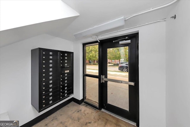 doorway to outside featuring concrete flooring and a mail area