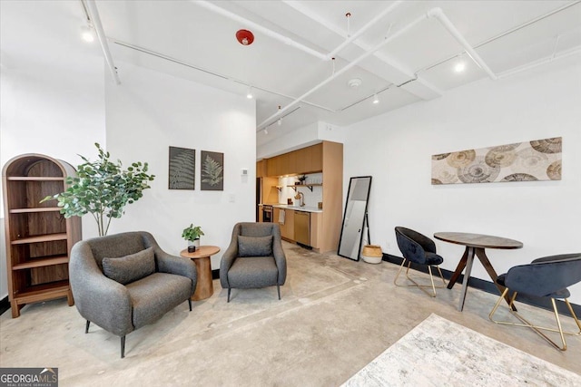 living area featuring track lighting, sink, and a high ceiling