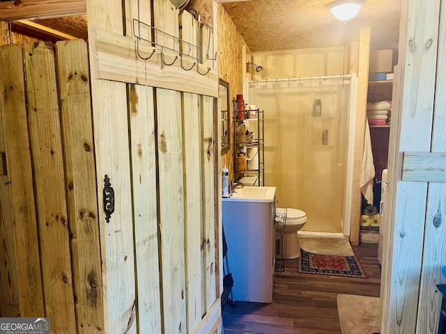 bathroom with wood-type flooring, toilet, vanity, and a shower with curtain