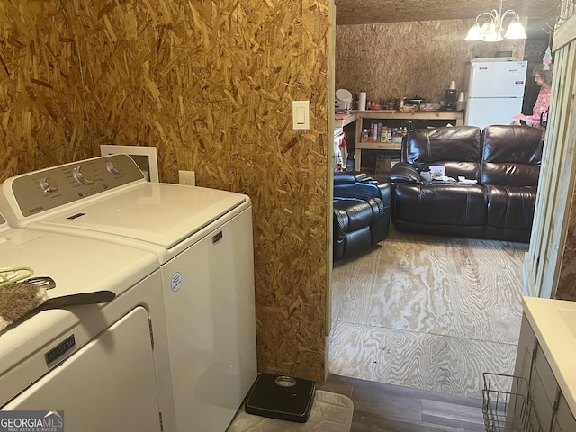 laundry room featuring wood-type flooring, washer and dryer, and a chandelier