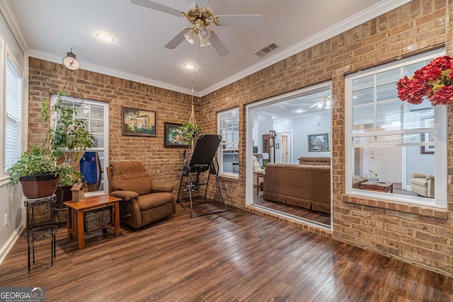 sitting room featuring crown molding, hardwood / wood-style flooring, ceiling fan, and brick wall