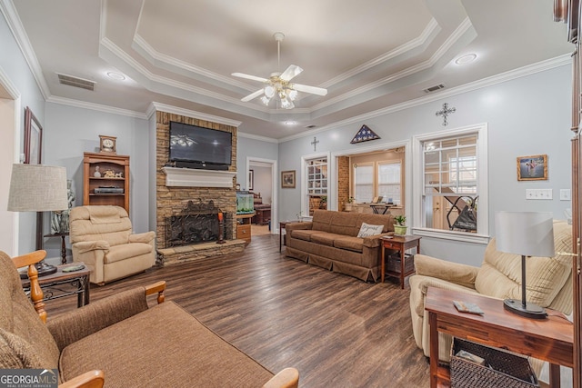 living room with crown molding, ceiling fan, a fireplace, dark hardwood / wood-style flooring, and a raised ceiling