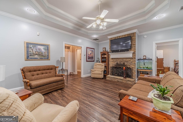 living room with a raised ceiling, ceiling fan, dark hardwood / wood-style floors, and a fireplace