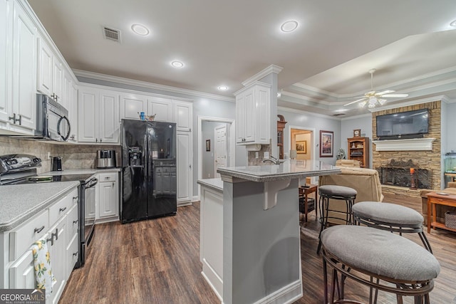 kitchen with white cabinetry, backsplash, a fireplace, and black appliances