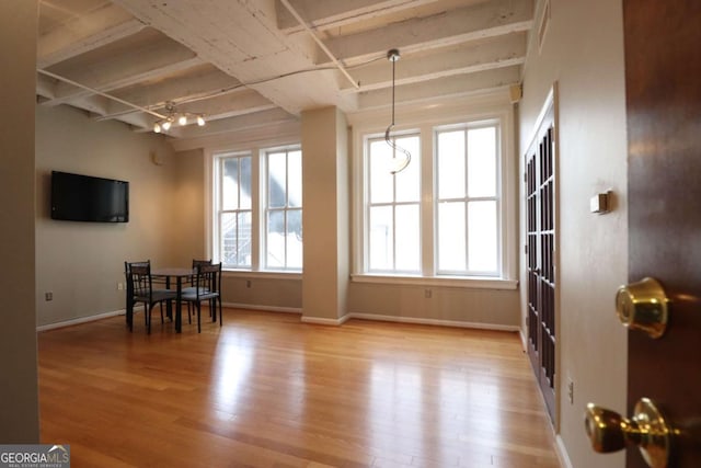 dining space featuring beamed ceiling and light wood-type flooring