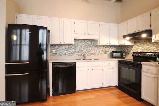 kitchen featuring sink, white cabinetry, tasteful backsplash, light wood-type flooring, and black appliances