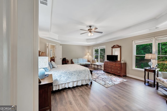 bedroom featuring hardwood / wood-style floors, a tray ceiling, ornamental molding, and ceiling fan