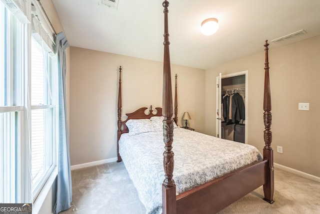 bedroom featuring light colored carpet, a spacious closet, and multiple windows