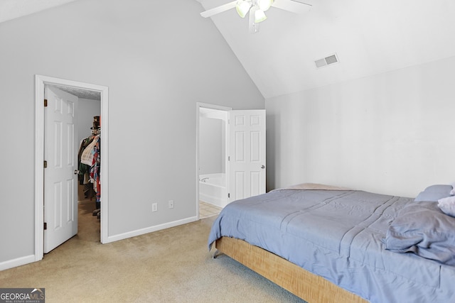 carpeted bedroom with a spacious closet, ensuite bath, high vaulted ceiling, and ceiling fan