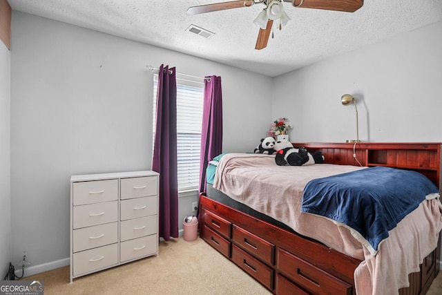 bedroom with ceiling fan, light carpet, and a textured ceiling