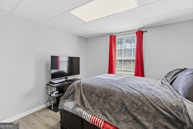 bedroom with a paneled ceiling and light wood-type flooring