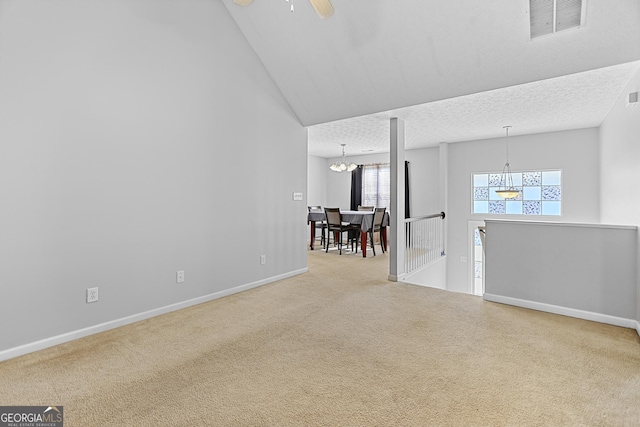 carpeted empty room with ceiling fan with notable chandelier and a textured ceiling